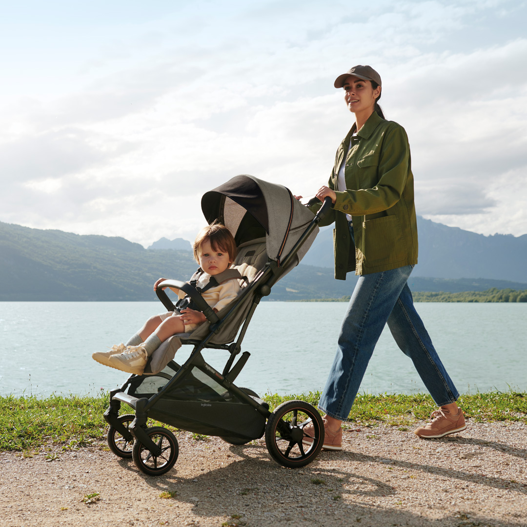 mamá paseando a su bebé con un carrito Inglesina a la vera de un lago